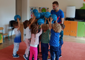 Dzieci przygotowują się do okrzyku dotykając że sobą piłki trzymane w rączkach.
